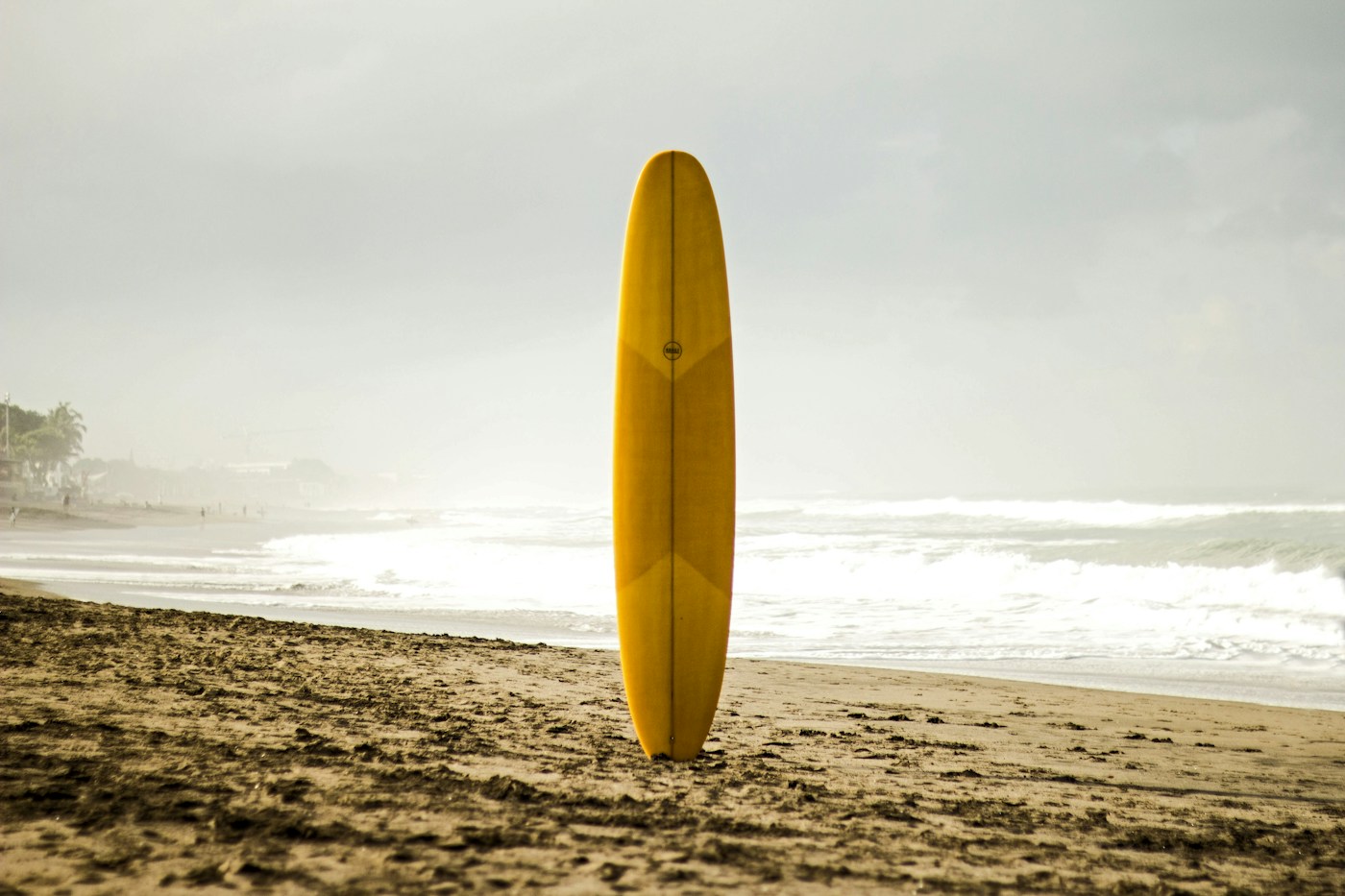 Prancha amarela na areia, em uma fotografia ilustrativa de surfe