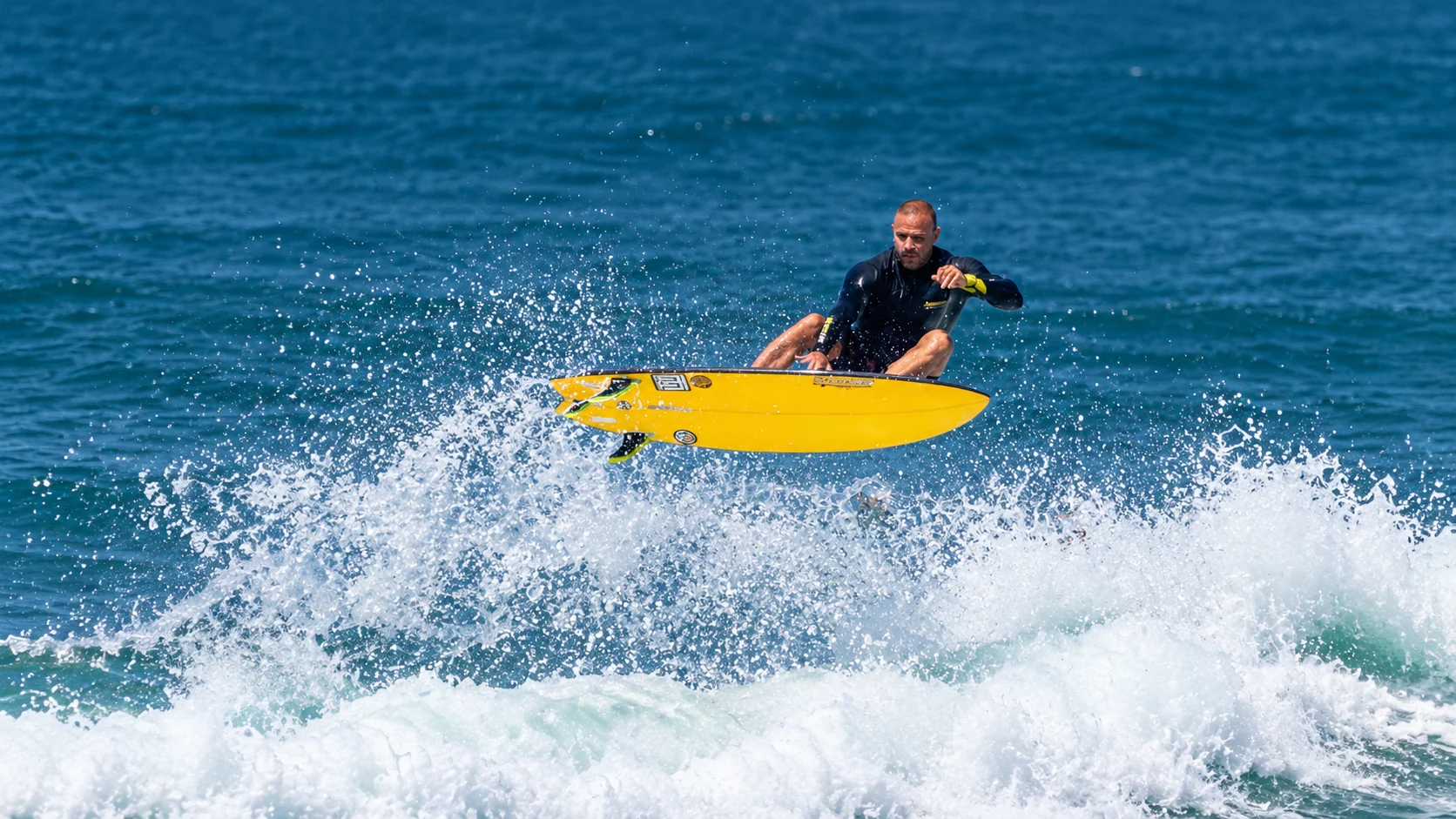 O dono da SURFLIFE em uma manobra de surfe com sua prancha amarela