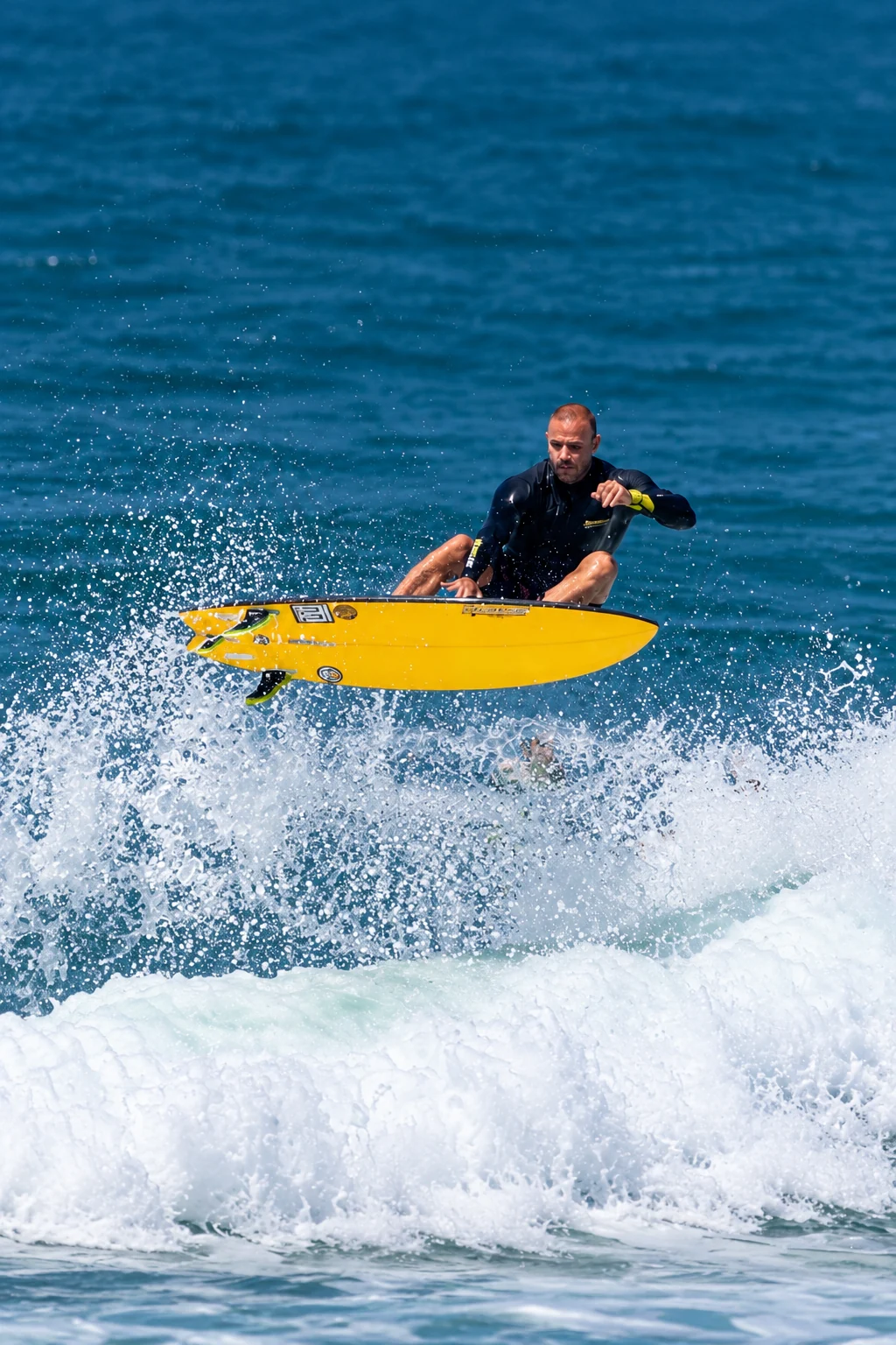O dono da SURFLIFE vivendo o surfe, sobre uma prancha amarela